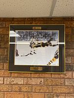 Full view of framed commemorative print hanging against brick wall
