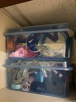 Two large translucent plastic bins stacked containing assorted ribbons and crafting materials.
