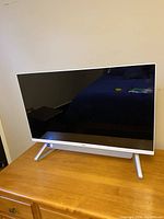 Front view of all-in-one computer showing screen, bezel and stand on wooden surface