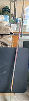 Full length view of the Easton hockey stick, showing its straight wooden blade and long shaft with red branding.