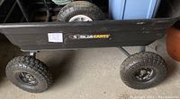 Side view of black plastic tub on steel frame with brand sticker and four pneumatic tread wheels