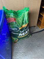Large green bag of Scotts Turf Builder Lawn Food with iron supplement, located on garage floor.