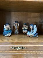 Four Lladro Inuit figurines displayed on a wooden shelf