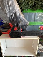 Side view of the Craftsman battery-powered chainsaw with cover on the bar, showing the full body and handle.