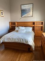 Full view of queen bed showing wood headboard with shelves, platform frame, nightstands and bedding.