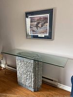 Full view of the glass top sofa table against living room wall under framed artwork