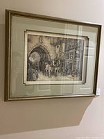 Framed wall art featuring an old street scene with horse-drawn carriage under archway.