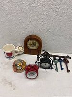 Photo showing all items in the lot including clocks, keys, mug, and cat figurine clock