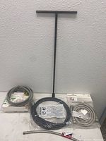 Black metal water shut off tool with T-shaped handle with three packaged hoses and cords.