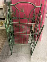 Front view of green metal 3-shelf rack showing bamboo design on back panel and wire shelves.