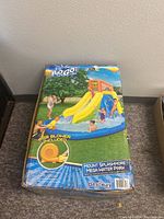 Box front showing inflatable water park with slides, kids playing, and blower included