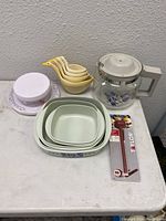 View showing all kitchen items including CorningWare bakeware, yellow measuring cups, covered butter dish, and thermometer.