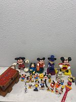 Full lot showing all Mickey Mouse and Disney character collectible figures and toys arranged on white surface.