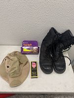 Photo showing black military boots, camo boonie hat, Visi-belt in package, and leather cleaner bottle.