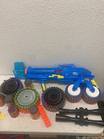 Blue Nerf blaster with multiple foam dart drum magazines and accessories on a white surface