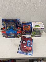 Overview of lot showing Akedo Ultimate Battle Arena set, Hot Wheels car, Funko Pop Hulk figure, and Spider-Man phone case.