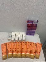Lot of wrinkle creams and moisturizers arranged on a table showing orange, white tubes, and purple boxes.