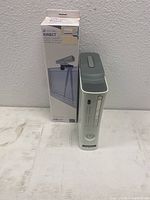 White Xbox 360 console standing vertically next to Kinect sensor box showing the product image.