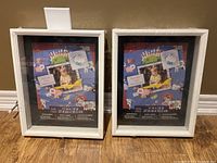 Two white shadow boxes standing upright against a wall, showing the front glass and placeholder image.
