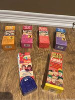 Photo of six Brain Quest children's educational card games for various age groups and grades, colorful packaging with illustrations and text describing question counts and age range.