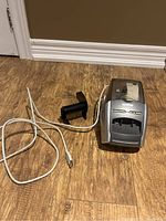 Full view of Brother label printer on floor with USB cable attached and black handheld scanner placed beside it.