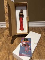 Maasai clay sculpture in packaging with white foam and informational booklet beside it.