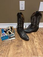 Overall view of cowboy boots with box of shoe cleaning products to the side on wooden floor