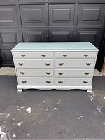 Front view of white dresser with eight drawers on asphalt