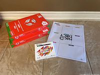Photo showing two unopened Cougar reams of 8.5x14 legal paper, one pack of Volcano Magnetic dry erase markers, and a Mac Fancy dry erase magnetic weekly calendar sheet laid flat on floor.