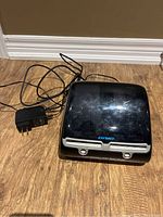 Front view of printer on wood floor with power adapter and cables coiled beside it