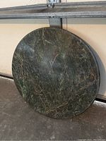 Top view of the circular marble table top showing green and black marble veining.