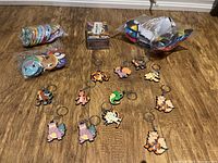 Entire lot displaying 14 Pokémon keychains, three fold-up balls, and the boxed Charizard cards on a wood floor.