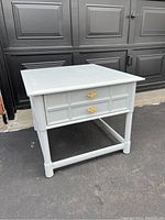 Front side view of white painted side table showing drawer and gold hardware.