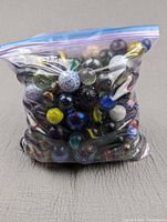 Photo of a sealed plastic bag filled with assorted shooter marbles of various colors and patterns, weighing 12.6 pounds as stated by the seller.