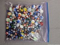 Plastic zipper bag filled with a variety of mixed glass marbles in an assortment of colors and patterns.