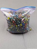 Clear plastic ziplock bag filled with numerous colorful cats eye glass marbles.