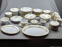 Full layout of all plates, bowls, cups, saucers and serving pieces on gray backdrop