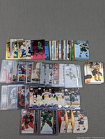 Photo shows a large assortment of hockey cards organized in rows, some in plastic sleeves and some loose, all featuring hockey players in various poses and team uniforms.