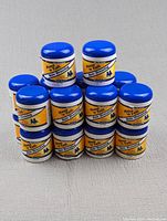 Eighteen jars of Mane 'n Tail Hair Dressing Conditioning & Styling stacked together showing the front labels and blue lids.