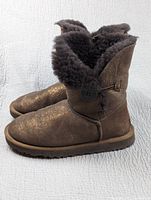 Side view of the pair of boots showing the metallic sparkle texture and button detail