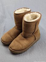 Pair of UGG boots viewed from a side angle showing the suede exterior and wool lining.