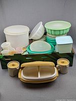 Photo showing assorted vintage Tupperware in a box, including bowls, containers, and lids in various pastel colors and white.