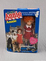 Front view of boxed Orphan Annie doll showing doll and packaging graphics