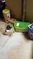 Wide view of all items including wooden block bucket, Duplo green tub, Lego bricks bag and train set box