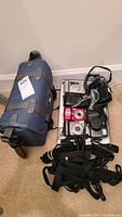 Photo showing Sony HandyCam case, multiple cameras, and camera straps