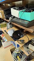 Shelf with fax machine, assorted cords, speaker components and other small electronics.