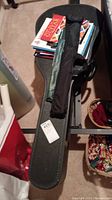 Hard guitar case with soft carrying bag placed on top along with a stack of guitar instruction books.