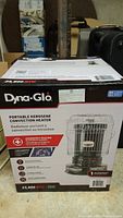 Front view of the boxed Dyna-Glo portable kerosene convection heater showing brand, BTU rating, and emergency heating usage info