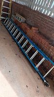 Full length view of ladder collapsed on ground against brick wall