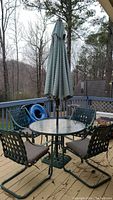 Full patio set including table with umbrella, four chairs with cushions, set on deck outdoors